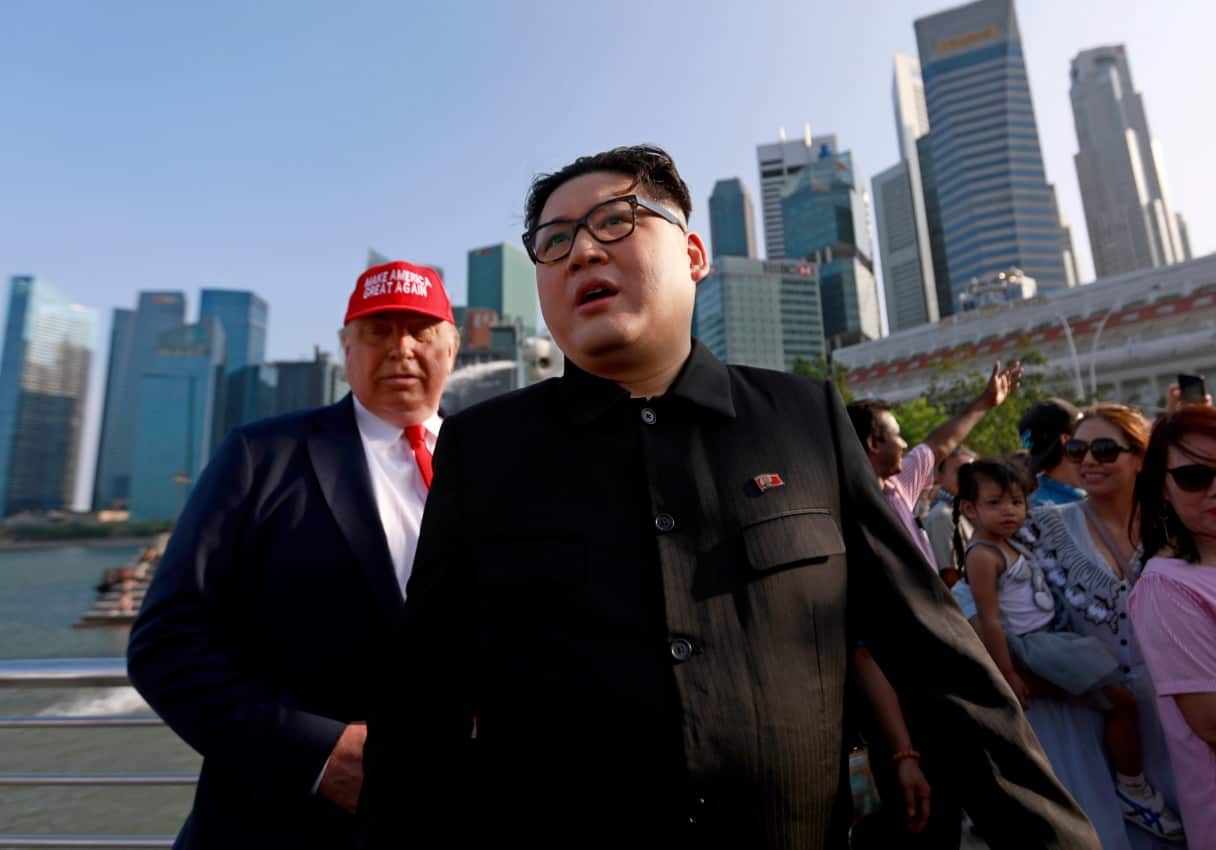 Kim Jong-Un impersonator Howard X (C) and Donald Trump impersonator Dennis Alan (L) walk together at the Merlion Park in Singapore, 08 June 2018.