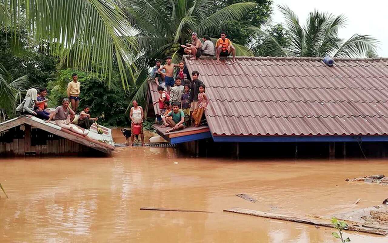 Lao villagers are seen stranded on rooftops of houses to evacuate from floodwaters after the dam collapse. 