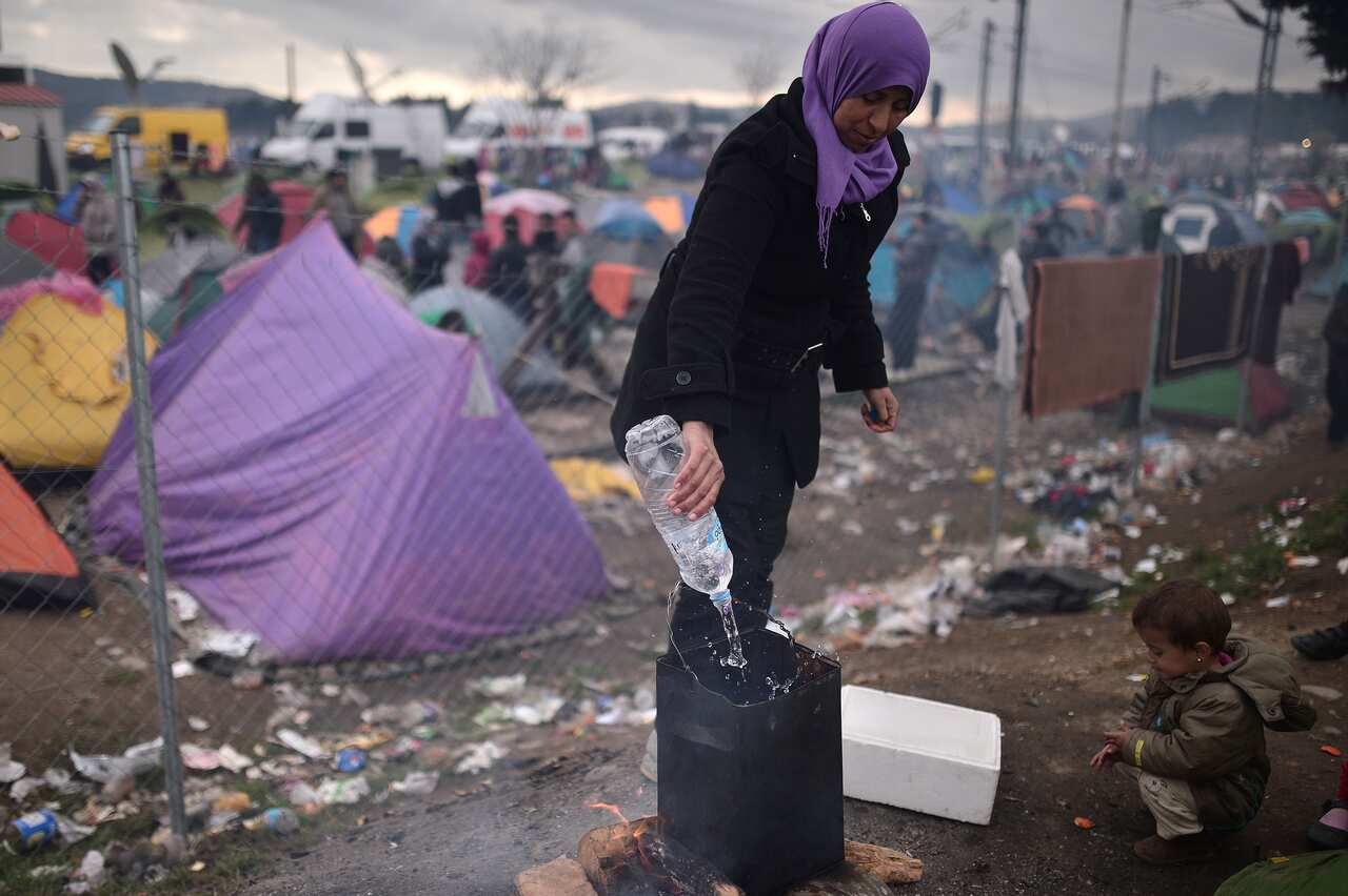 A woman boils water in the makeshift camp at the Greek-Macedonian border near the village of Idomeni.