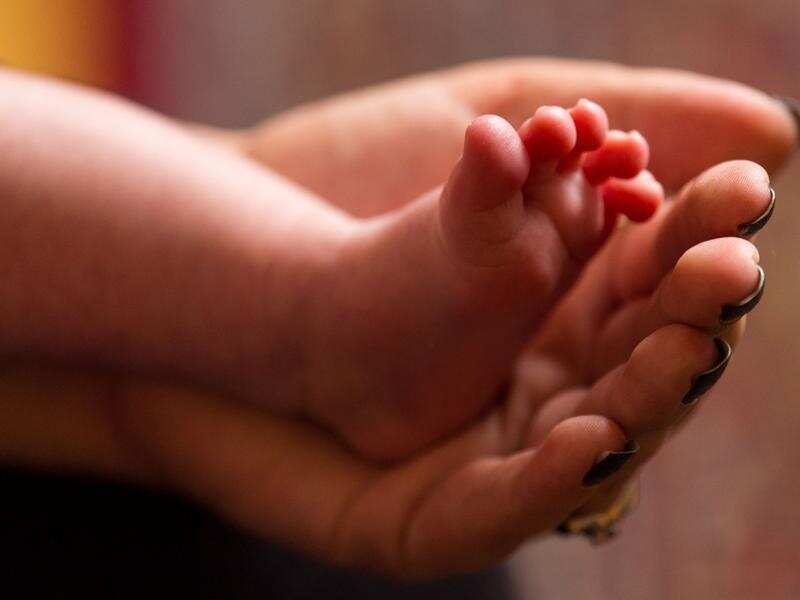 a mother holding the feet of a new baby