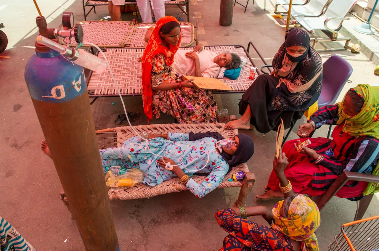 A COVID-19 patient is seen breathing through an oxygen mask with an oxygen cylinder outside Gurudwara Sri Guru Singh Sabha Indirapuram.