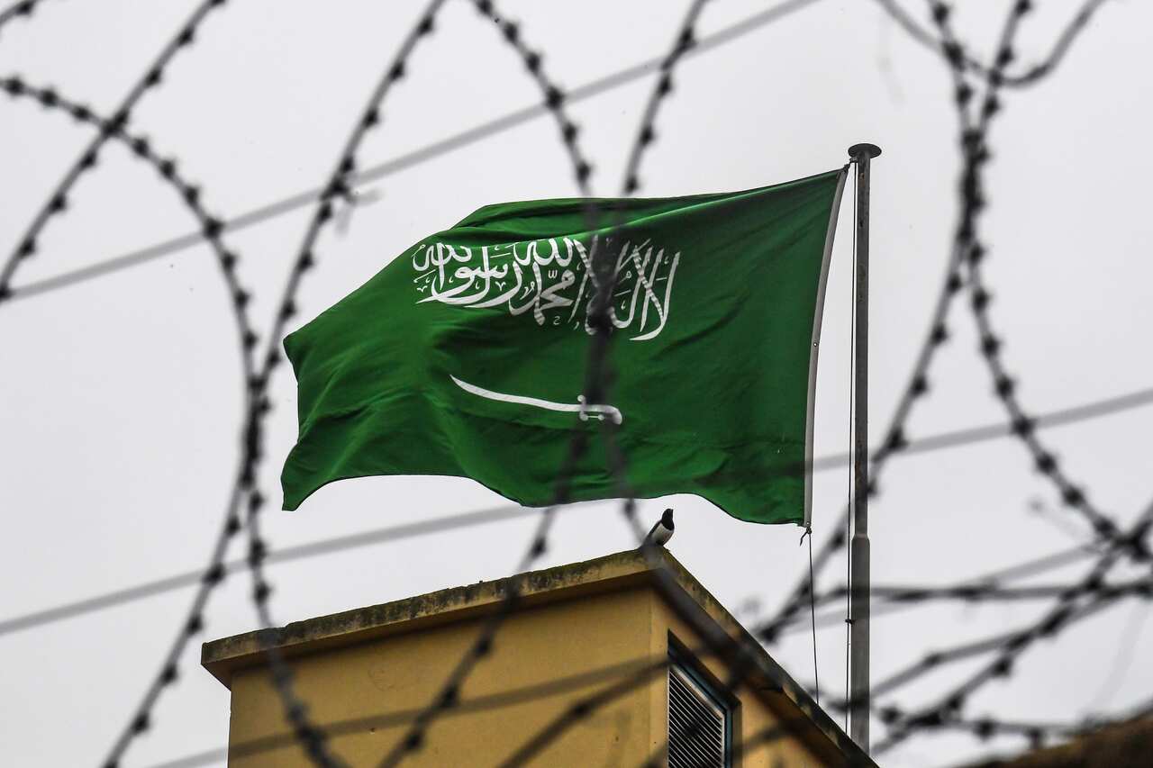 The Saudi Arabian flag is seen behind barbed wire as it flies on the roof at the Saudi Arabian consulate in Istanbul on October 14, 2018. 