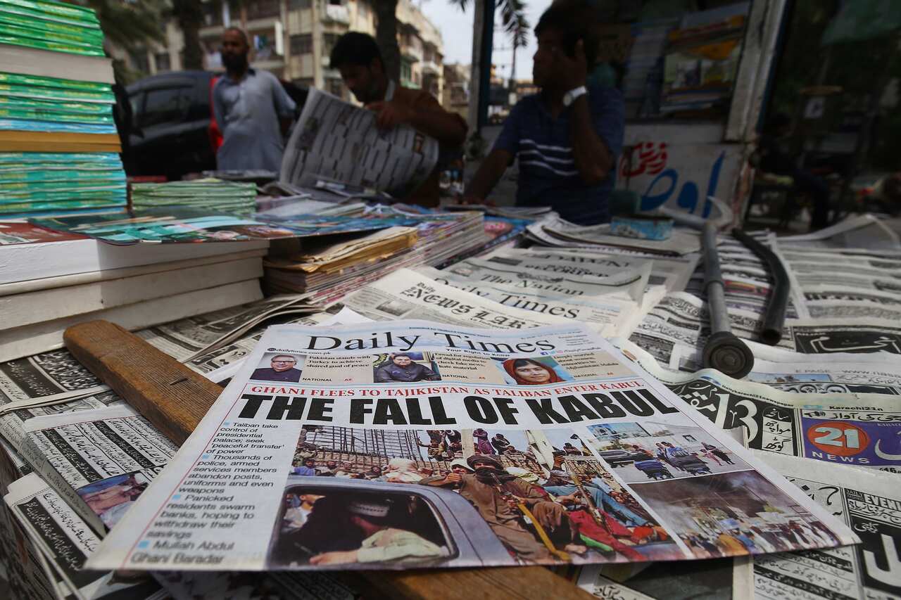 People read newspapers about the Taliban taking over Kabul at a stall in Karachi, Pakistan, 16 August 2021. 