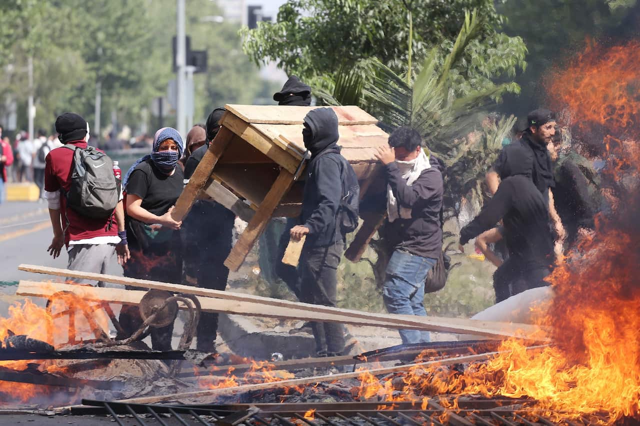 People burn objects as demonstrations against the increase of Metro fares take place, in Santiago, Chile, 19 October 2019.
