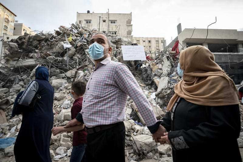 A family passes the rubble from a building previously destroyed in an air-strike in Gaza after a ceasefire was reached