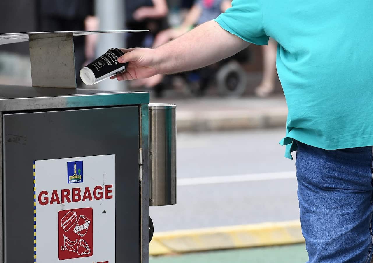 A man disposes of a coffee cup into a rubbish bin in Brisbane.               