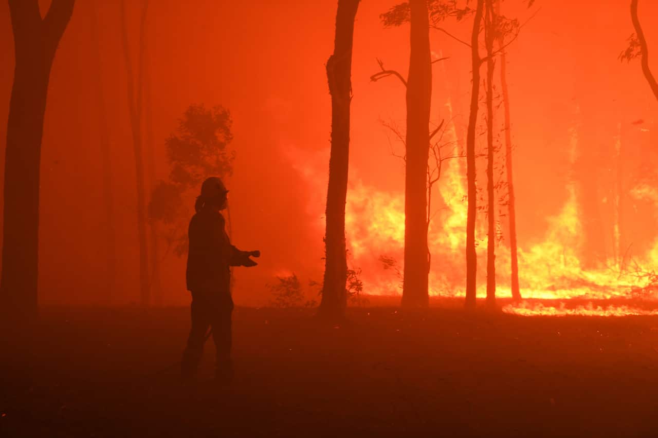 RFS volunteers and NSW Fire and Rescue officers protect a home on Wheelbarrow Ridge Road being impacted by the Gospers Mountain fire near Colo Heights south west of Sydney, Tuesday, November 19, 2019. (AAP Image/Dean Lewins) NO ARCHIVING