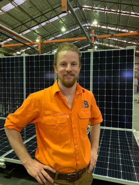 Chris McGrath of 5B Solar stands in front of some solar panels
