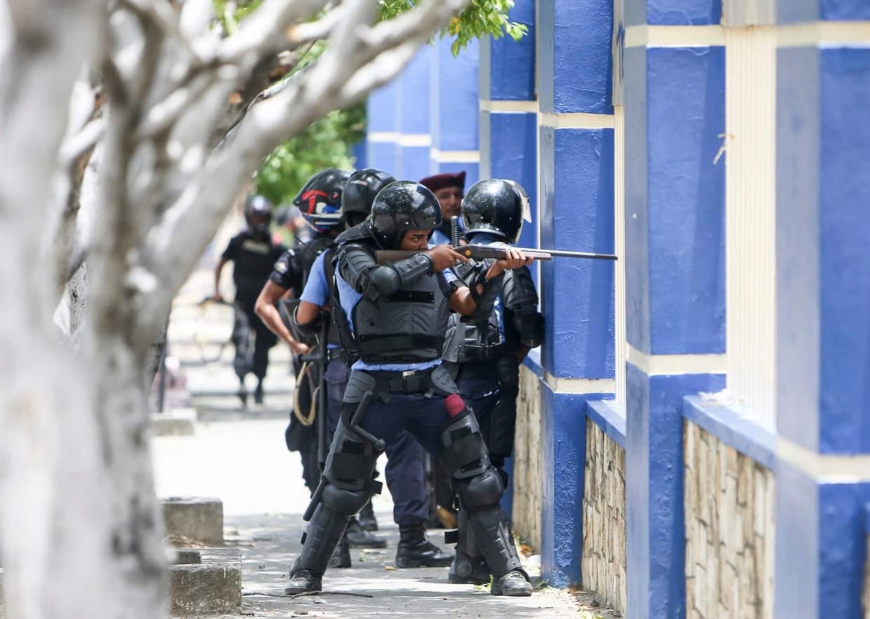 A police officer aims his weapon at demonstrators during clashes in Managua, Nicaragua, on Friday.