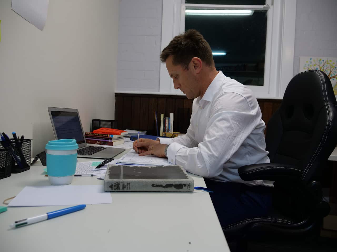 A man in a dress shirt working at a desk.