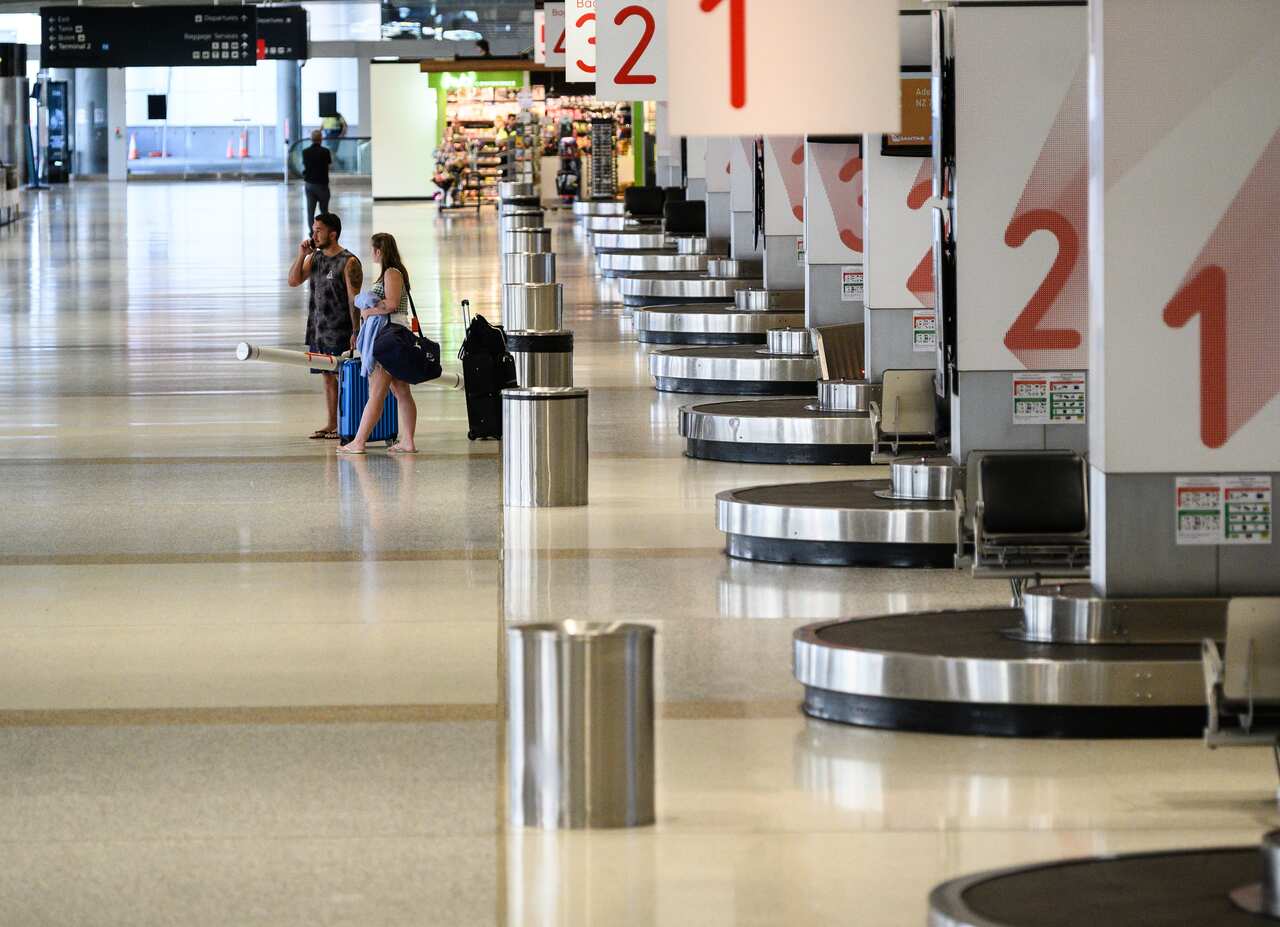 Passengers in an usually quiet baggage arrivals area at Sydney Domestic Airport, Friday, March 20, 2020.