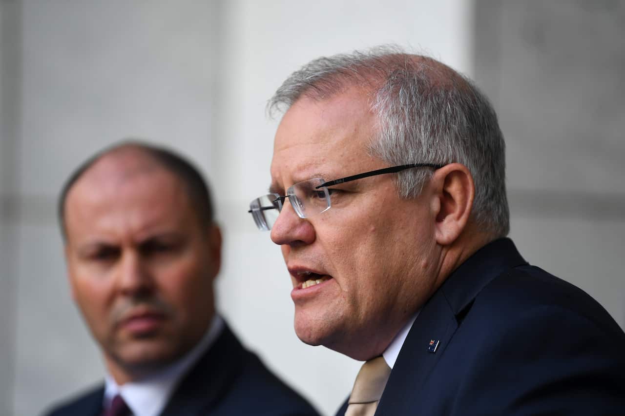 Treasurer Josh Frydenberg listens as Prime Minister Scott Morrison addresses economic stimulus measures.
