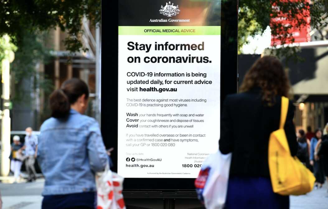 Shoppers and workers walk past an official medical advice sign in Pitt Street Mall, Sydney