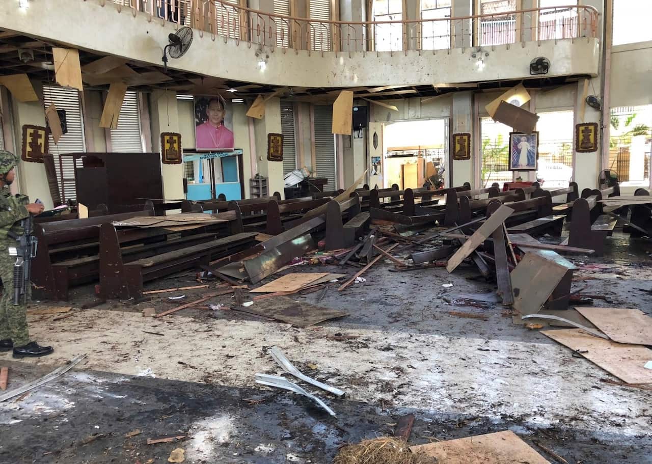In this photo provided by WESMINCOM Armed Forces of the Philippines, a soldier views the site inside a Roman Catholic cathedral in Jolo