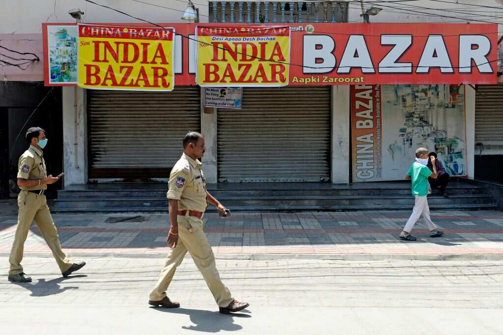Police personnel walk past in front of China Bazar, a shop selling Chinese made products, after it was closed and renamed as India Bazar, in Hyderabad, India.
