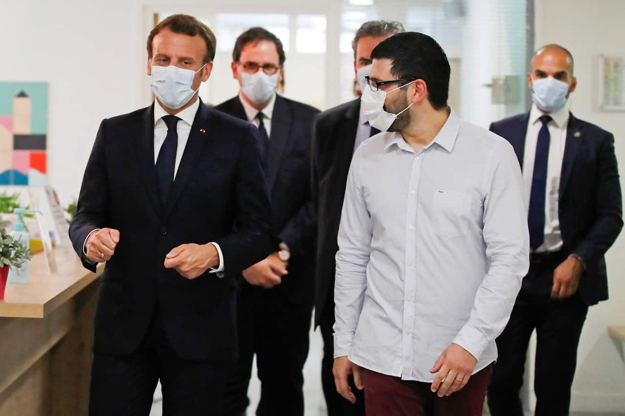 French President Emmanuel Macron, wearing a protective face mask, talks with health workers, 7 April, 2020. 