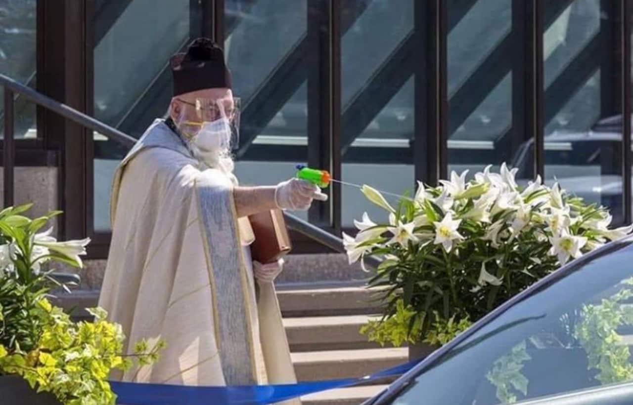 Father Timothy Pelc distributes holy water via his water gun.
