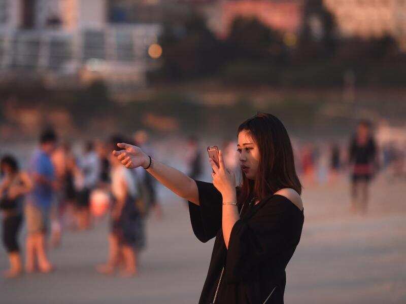 A woman from China takes a photo at Bondi beach.