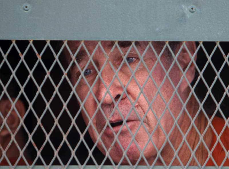 Ricketson talks from inside a prisoner truck upon his arrival at Phnom Penh Municipal Court in Phnom Penh, Cambodia.