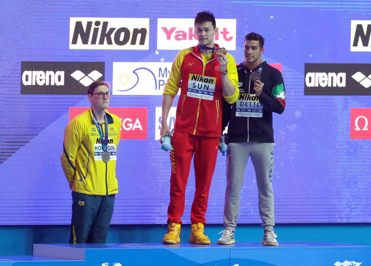 China's Sun Yang, centre, holds up his gold medal as silver medalist Australia's Mack Horton, left, stands away from the podium.