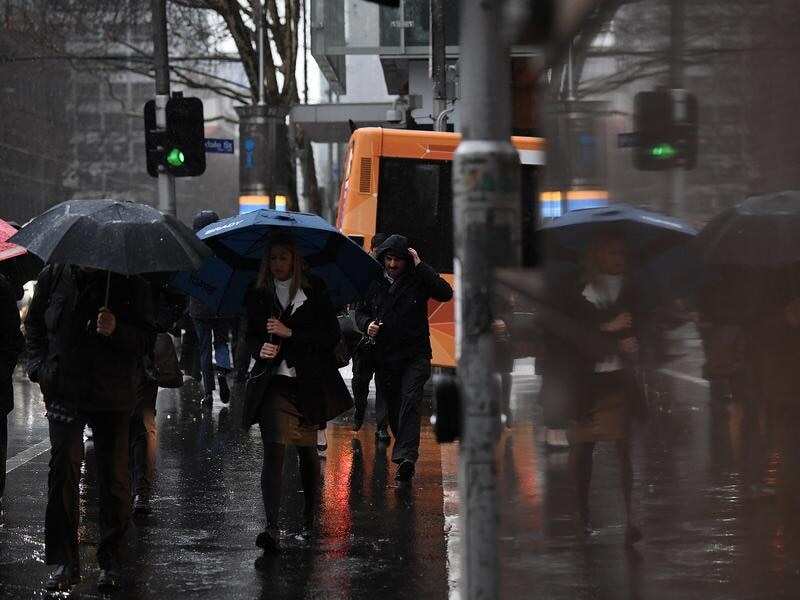 Pedestrians crossing an intersection during rain in Melbourne.