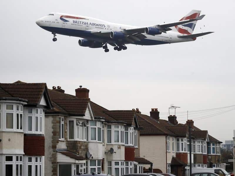 A plane nearby houses at Heathrow Airport.