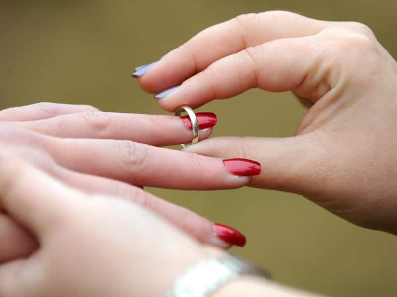 A woman places a wedding ring on her partners finger