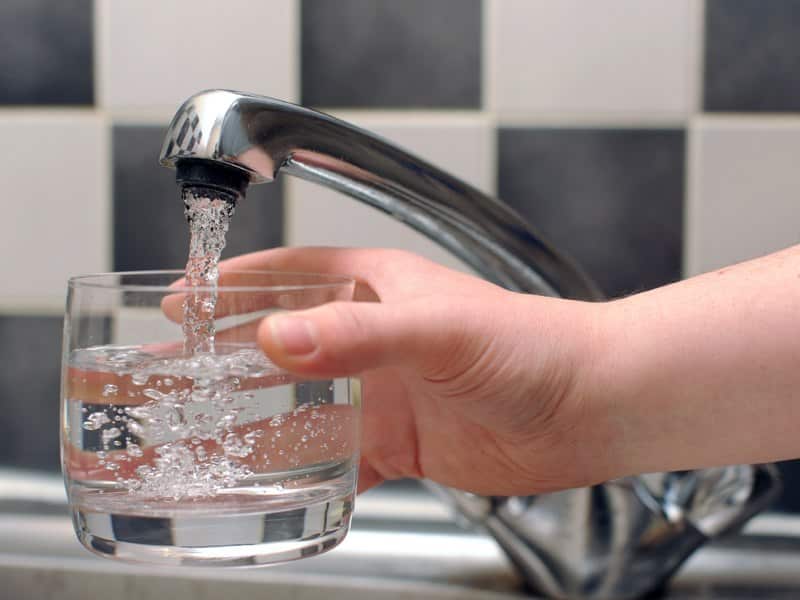 A person pours tap water into a glass