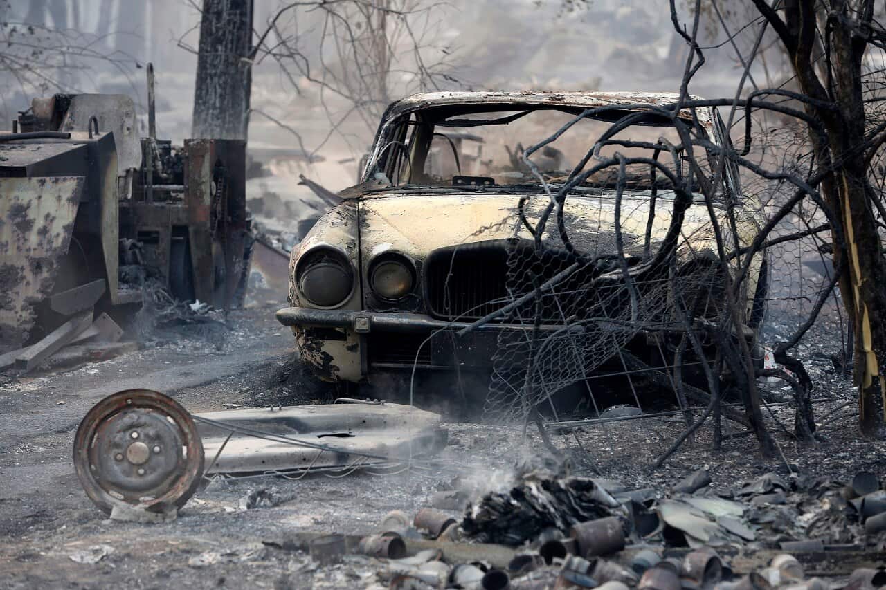 The burnt out shell of a Jaguar vehicle sits in the ruins of a smouldering house near Taree.
