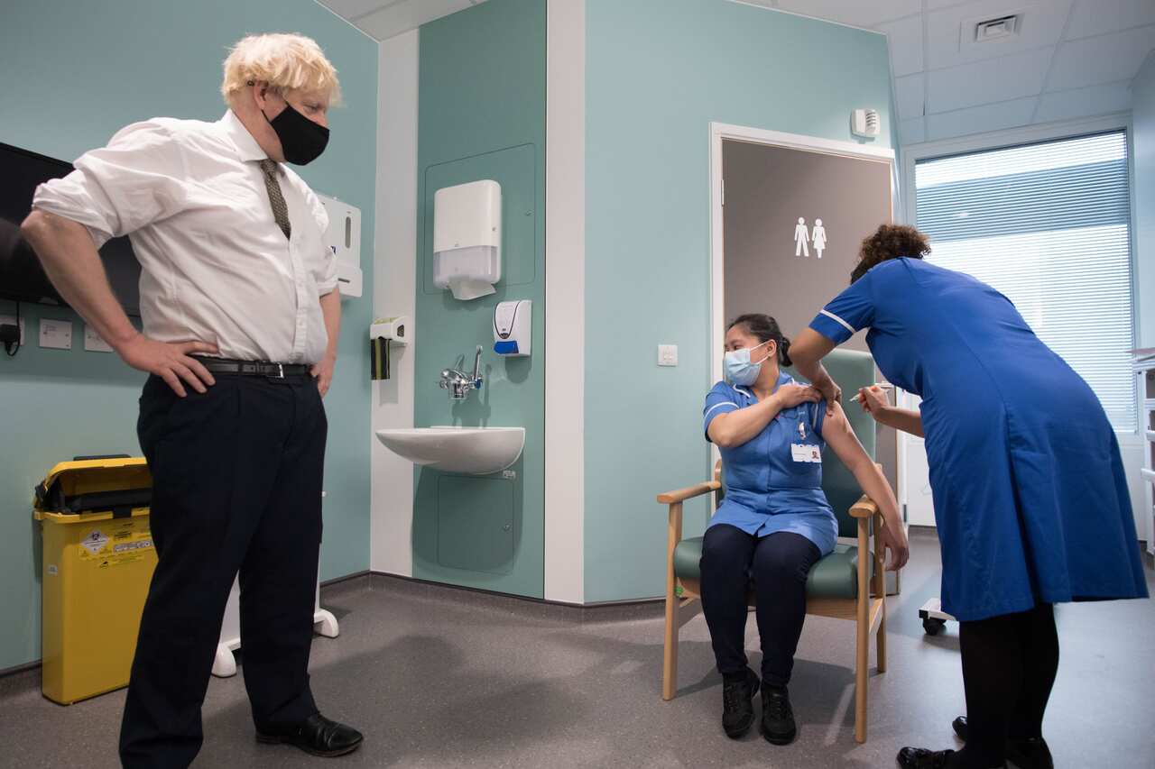 Prime Minister Boris Johnson watches as Jennifer Dumasi receives the Oxford/AstraZeneca COVID-19 vaccine at Chase Farm Hospital in north London on 4 January.