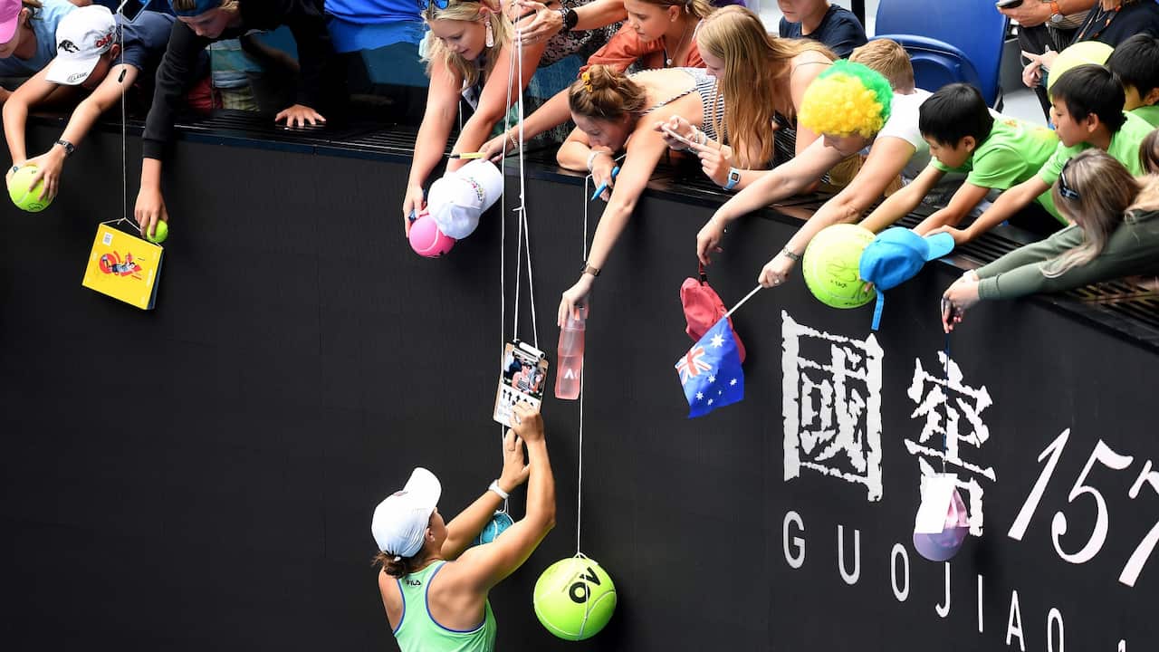 Ashleigh Barty of Australia signs autographs for fans after winning her third round match against Elena Rybakina of Kazakhstan.