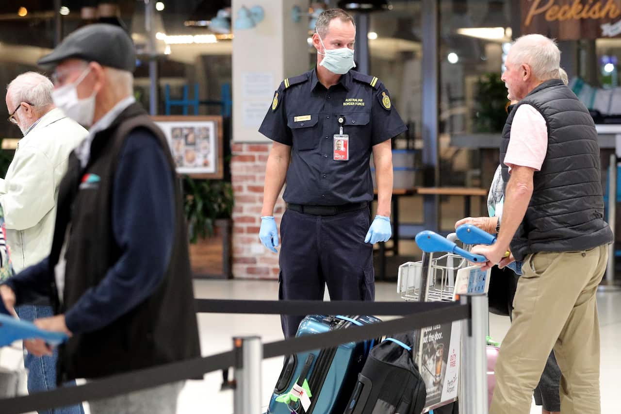 An Australia border Forcer official assists passengers.