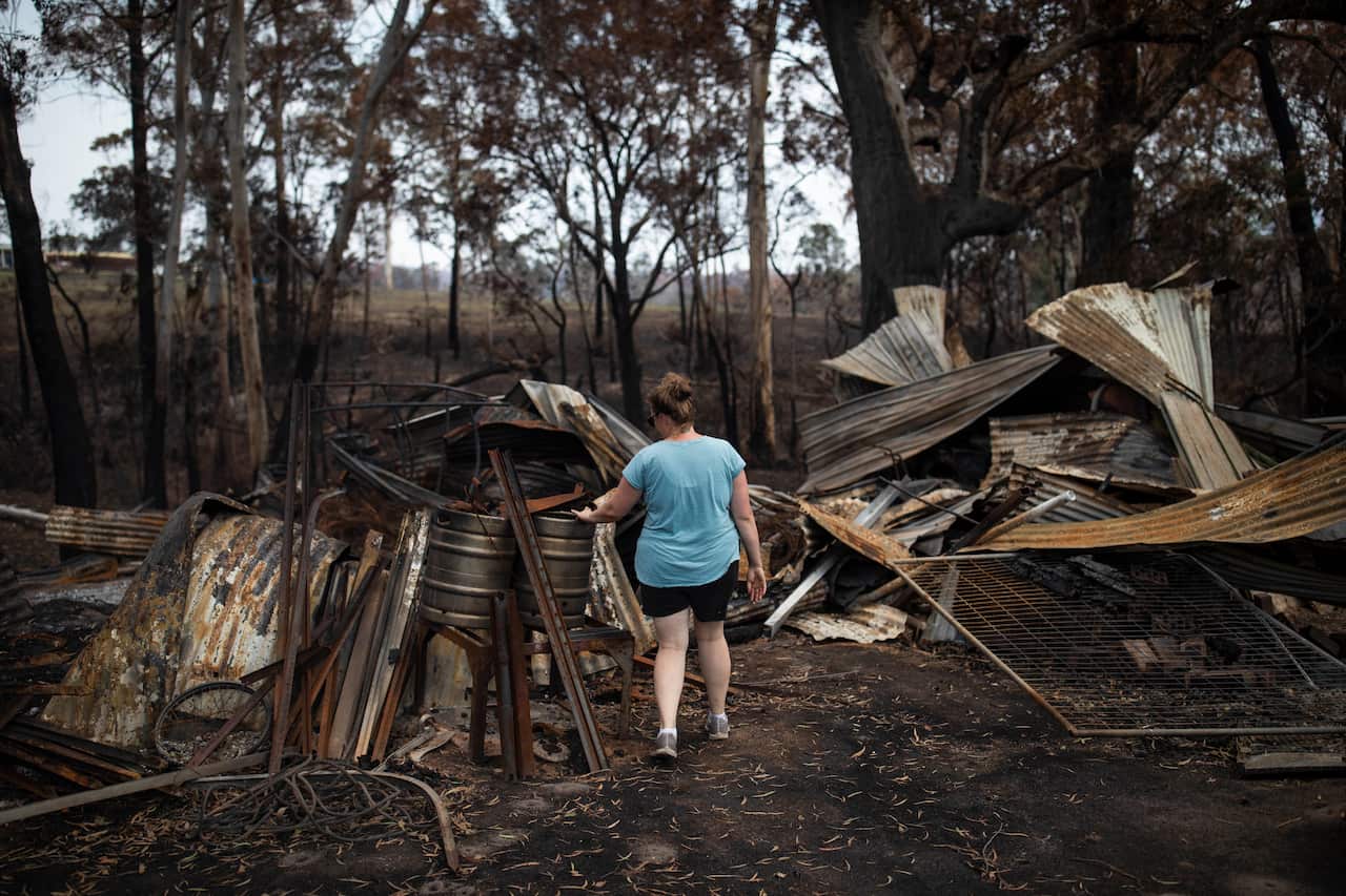A woman surveys property damage at Cobargo.
