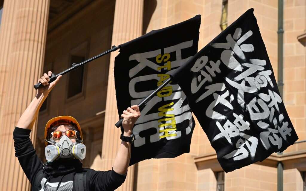 A supporter of the Hong Kong pro-democracy protesters waves flags during a demonstration as part of the global " movement in Sydney on September 29, 2019.
