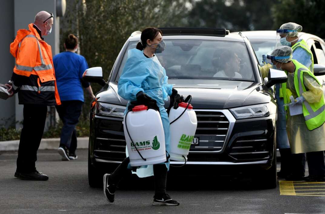 A cleaner dressed in Personal Protective Equipment (PPE) is seen leaving the Crossroads Hotel in Sydney, Saturday, July 11, 2020