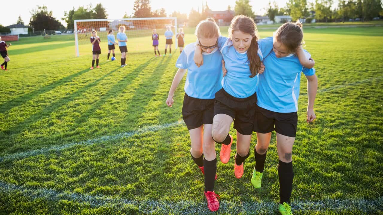 Girls helping injured soccer player off the field