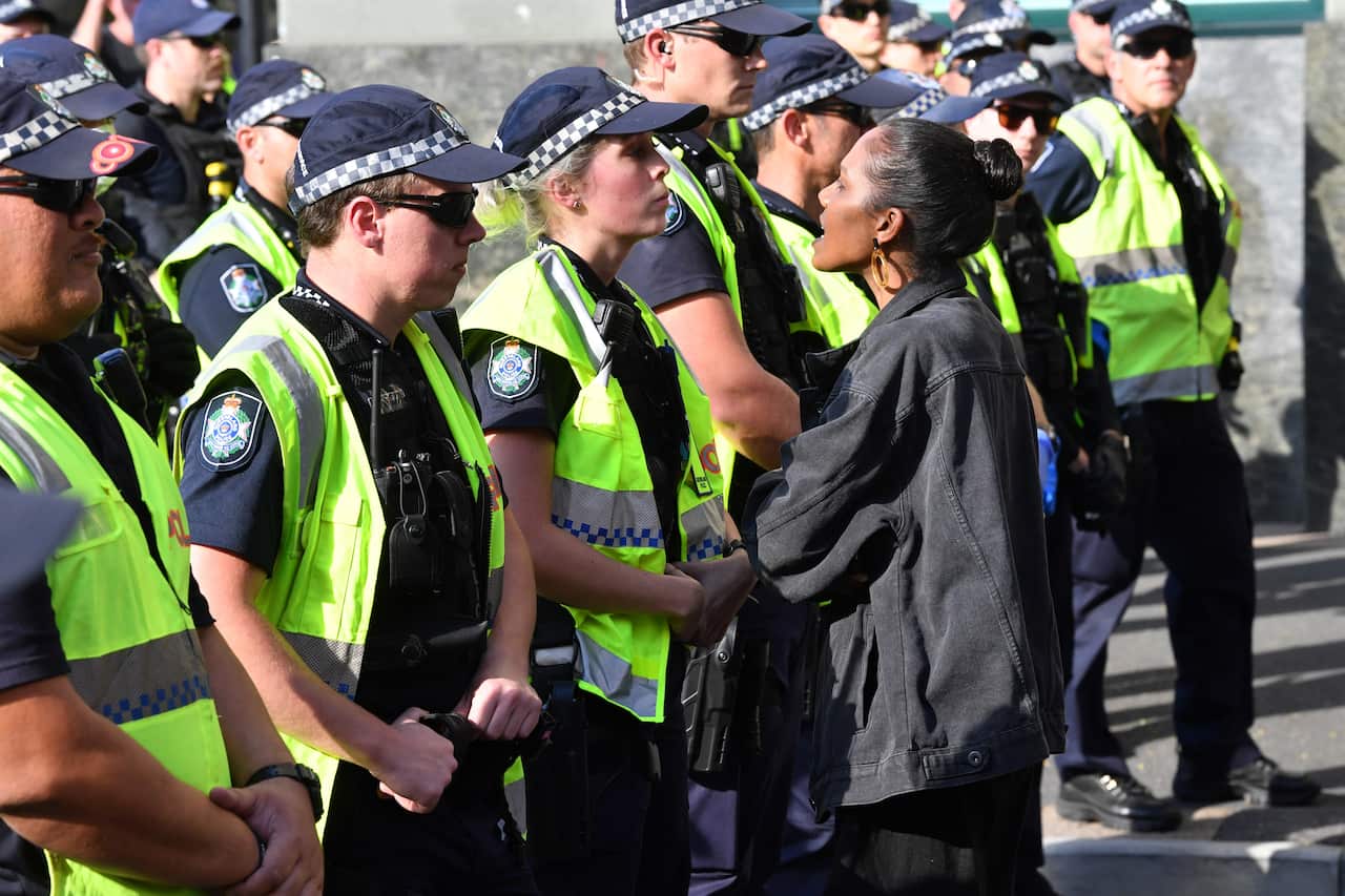 A Black Lives Matter protester confronts police officers during a protest outside the Roma Street Magistrates Court in Brisbane.