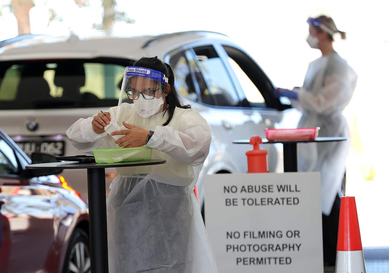 A health worker is seen as members of the public are seen queuing in their cars at a drive-through COVID-19 testing site at IPC Health Wyndham Vale, in Melbourne, Wednesday, December 29, 2021.