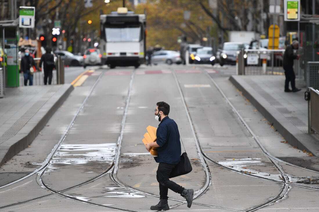 A person wearing a face mask crosses a street in Melbourne, Thursday, May 27, 2021