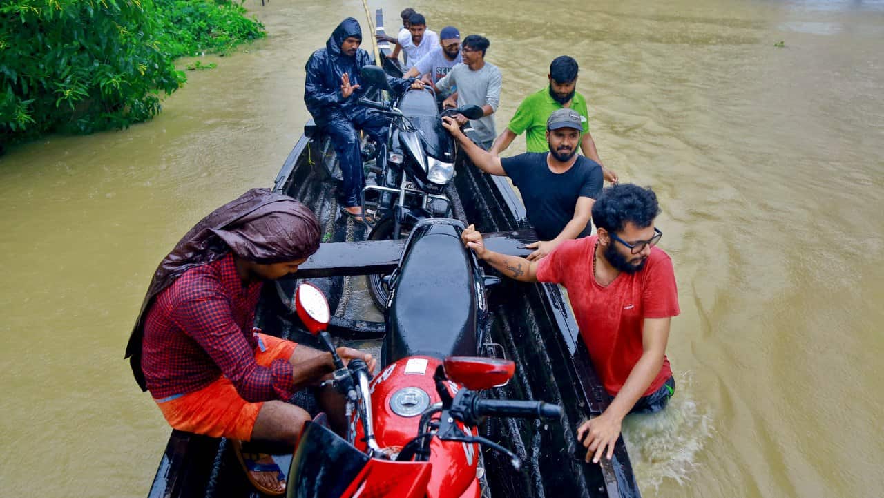 People salvage motorcycles in a country boat in a flooded area at Kainakary in Alappuzha district, Kerala state.