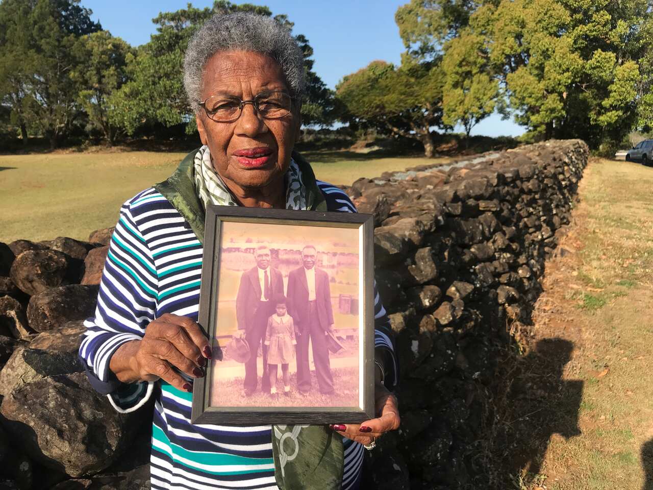 Aunty Lill Engstrom carries a photo of her father by the wall he build about 120 years ago. 