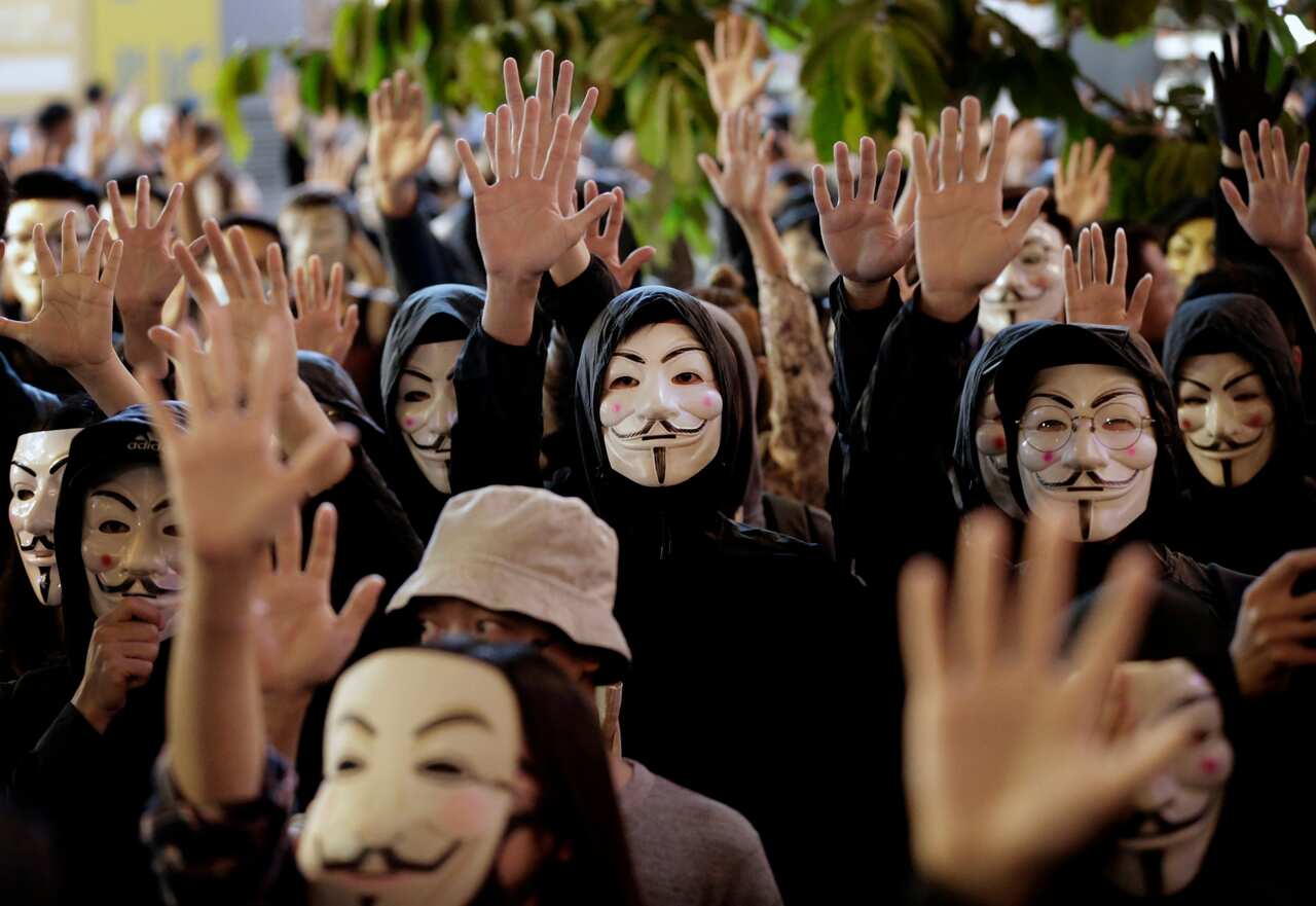 Protesters in Guy Fawkes masks raise their hands as they chant slogans during a rally in Hong Kong.