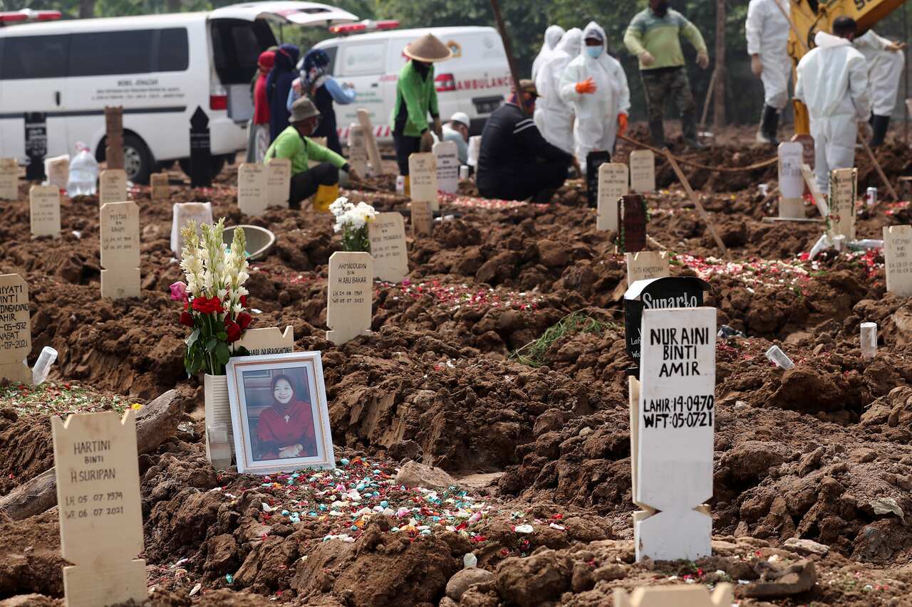 A portrait of a woman is laid on her grave at Rorotan Cemetery which is reserved for those who died of COVID-19, in Jakarta, Indonesia,Wednesday, 7July, 2021.
