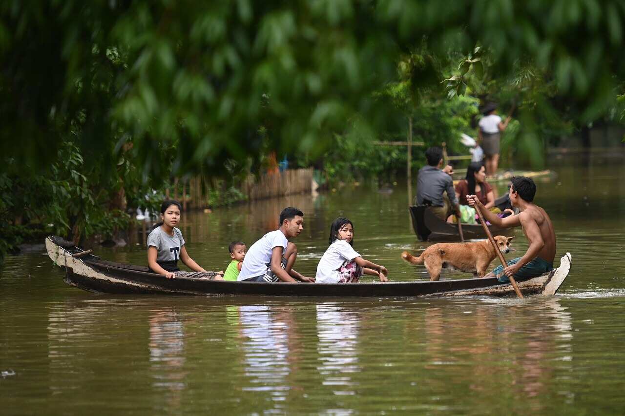 Residents ride in a boat through floodwaters in Bago.