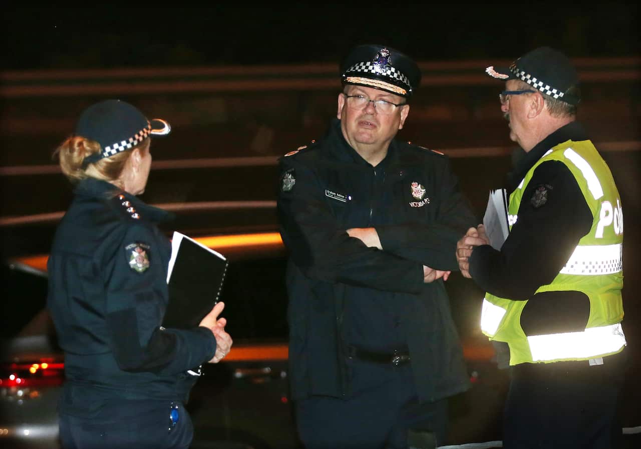 Victoria Police Chief Commissioner Graham Ashton (centre) is seen near where emergency services responded to the collision.
