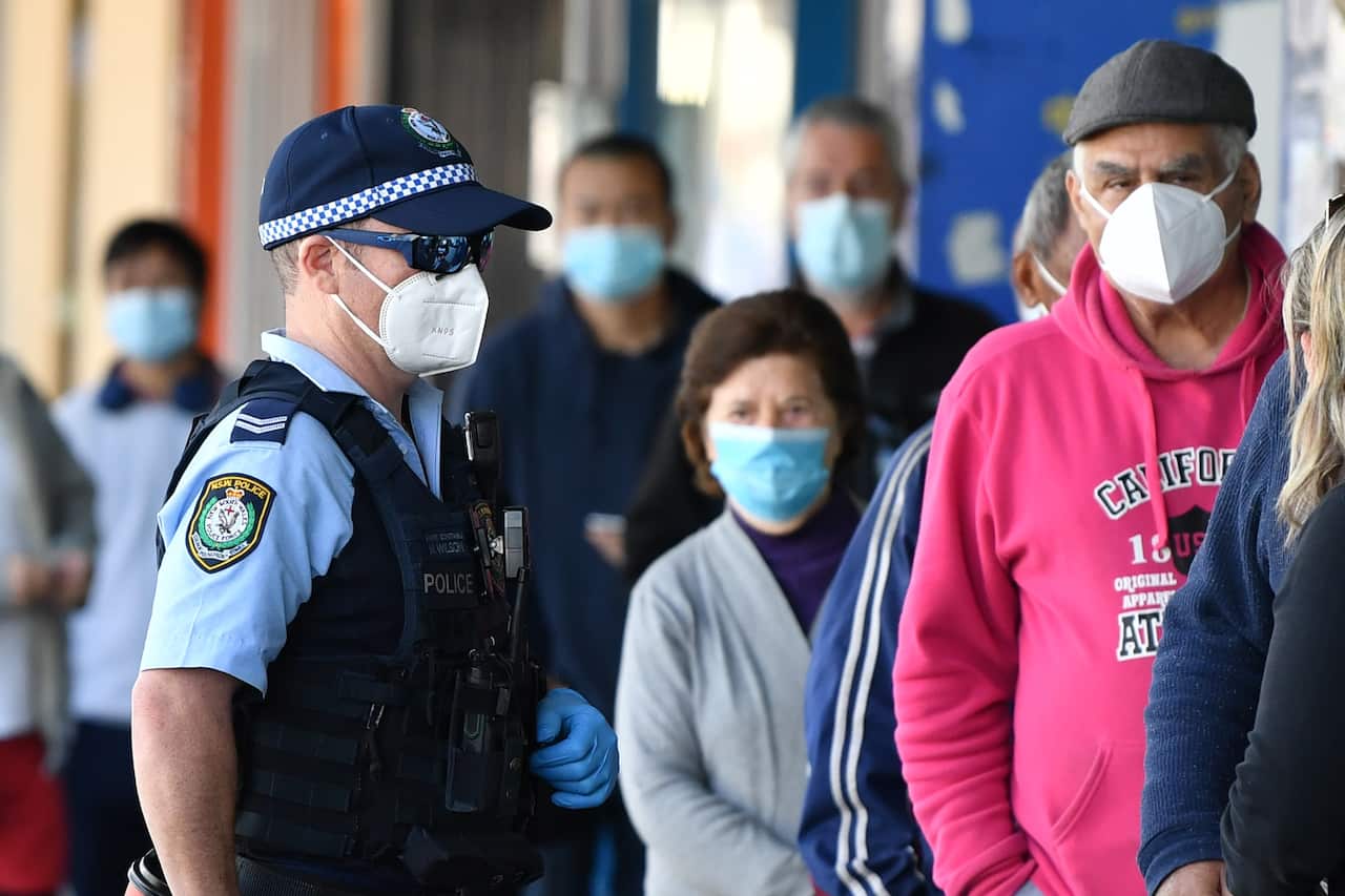 People wearing face masks wait outside a bank at Campsie in Sydney, August 19, 2021.