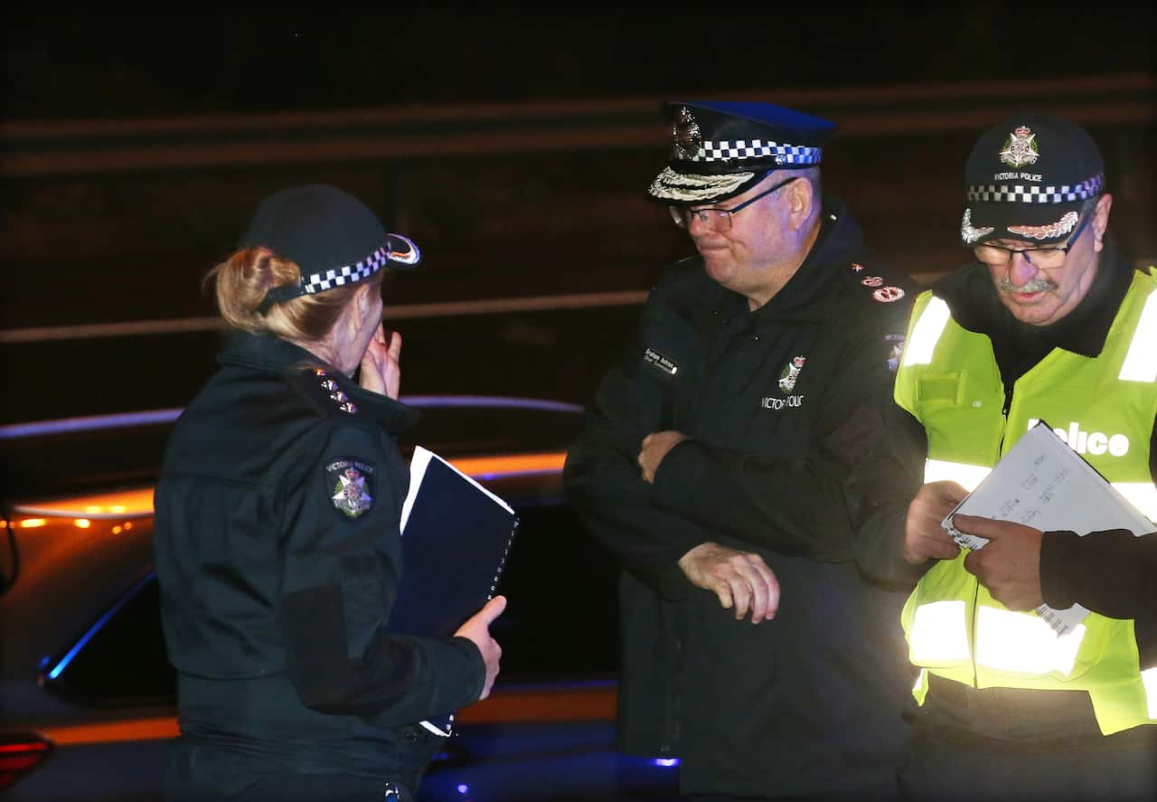 Victoria Police Chief Commissioner Graham Ashton (centre) is seen near where Emergency services responded to a collision in Melbourne.