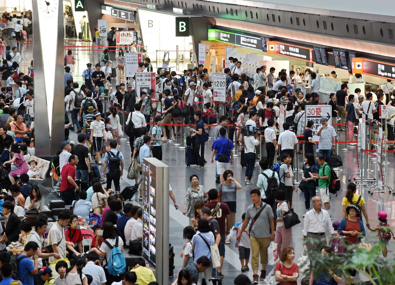 Travelers crowd the check-in area at Tokyo's Haneda Airport departure lounge as flights are delayed due to Typhoon Halong on August 9, 2014.