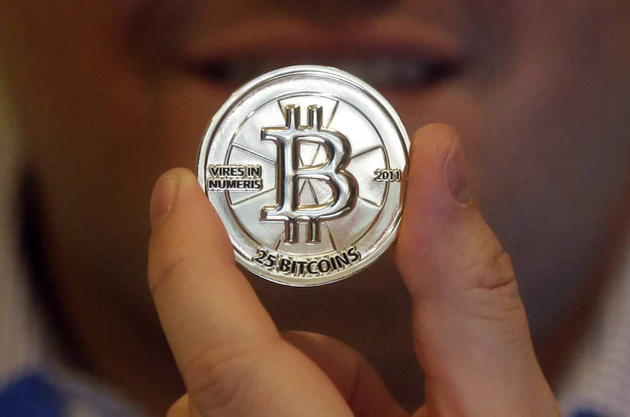  In this April 3, 2013 file photo, Mike Caldwell, a 35-year-old software engineer, holds a 25 Bitcoin token at his shop in Sandy, Utah.