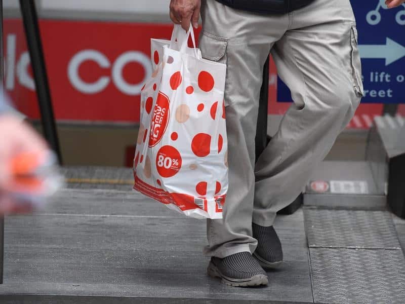 A shopper is seen carrying a reusable plastic bag at a Coles.